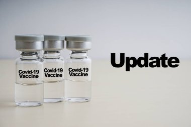 Tahta arka planda şişeler olan UPDATE metni. Coronavirus veya Covid-19 Aşı Konsepti