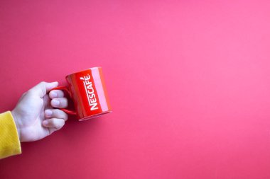 Kuala Lumpur, Malezya - 12 Kasım 2020: Kırmızı arka planda Nescafe Kupasını tutmak