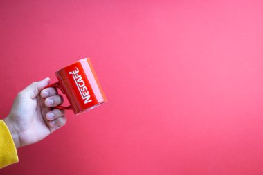 Kuala Lumpur, Malezya - 12 Kasım 2020: Kırmızı arka planda Nescafe Kupasını tutmak