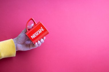Kuala Lumpur, Malezya - 12 Kasım 2020: Kırmızı arka planda Nescafe Kupasını tutmak