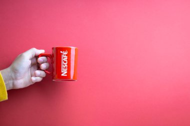 Kuala Lumpur, Malezya - 12 Kasım 2020: Kırmızı arka planda Nescafe Kupasını tutmak