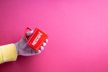Kuala Lumpur, Malezya - 12 Kasım 2020: Kırmızı arka planda Nescafe Kupasını tutmak