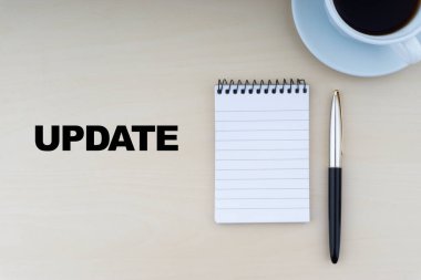 Dolma kalem, not defteri ve bir fincan kahveyle ahşap zemin üzerinde UPDATE metni. İş ve kopyalama alanı kavramı