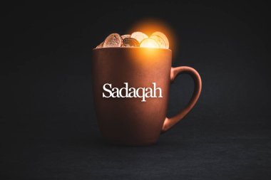 SADAQAH ya da Charity Hediye metni. Siyah arka planda madeni paralar var. Hayırseverlik Konsepti