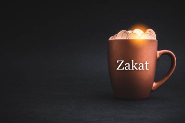 ZAKAT ya da ISLAMIC Vergi metni. Siyah arkaplanda madeni paralar var. Hayırseverlik Konsepti