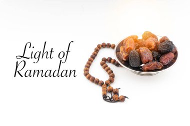 Beyaz zemin üzerinde hurma, kurma meyvesi, tespih ya da Tasbih olan RAMADAN metinlerinin Işığı. Ramazan Kareem ve İslam Kavramı
