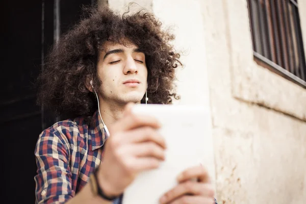 Joven escuchando música con tableta digital — Foto de Stock