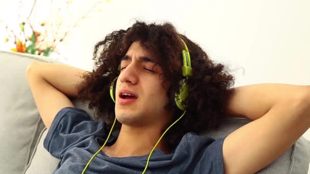Молодой человек слушает музыку в наушниках — стоковое видео