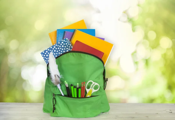 Backpack on wooden table in garden — Stock Photo, Image