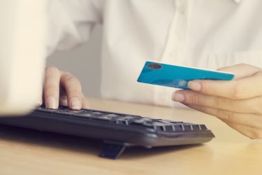 Kredi kartı tutan ve dizüstü bilgisayar kullanarak eller
