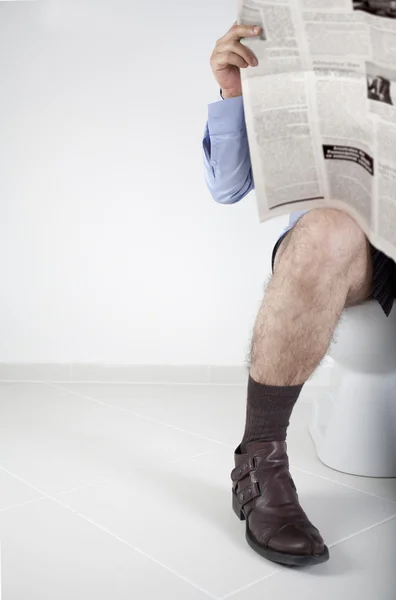 Muž, čtení novin v koupelně — Stock fotografie
