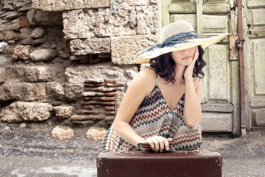 Bavul ile yolda oturan genç kadın