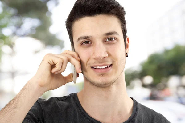 Młody człowiek mówi telefon komórkowy na ulicy — Zdjęcie stockowe