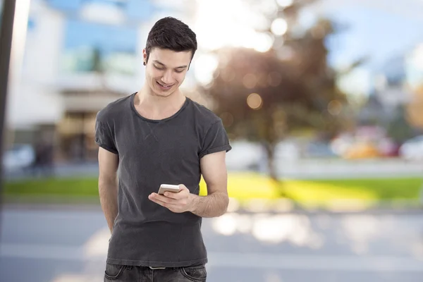 Šťastný mladý muž psaní zprávy na mobilním telefonu — Stock fotografie