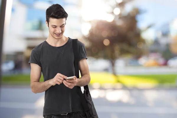 Happy young man writing message on mobile phone — Stock Photo, Image