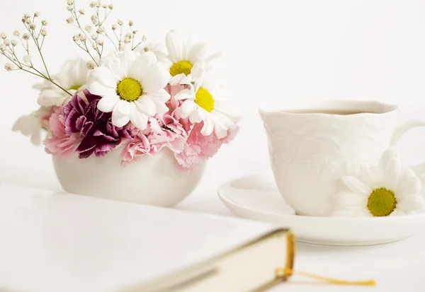 Bouquet av vakre blomster med en kopp og en bok – stockfoto