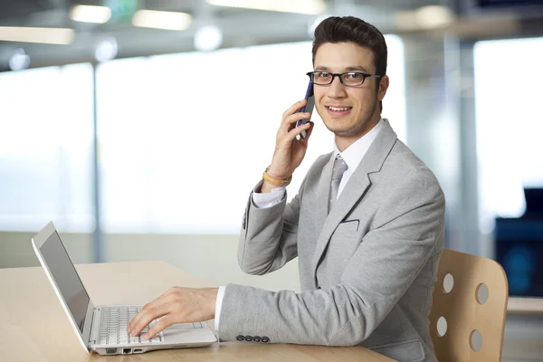 Empresário trabalhando em laptop e telefone falando — Fotografia de Stock