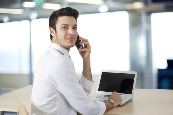 Бизнесмен, работающий над ноутбуком и говорящим телефоном — стоковое фото