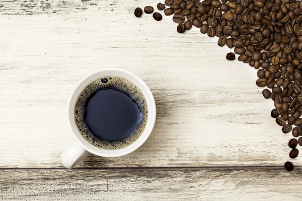 Xícara de café e grãos em uma mesa de madeira — Fotografia de Stock