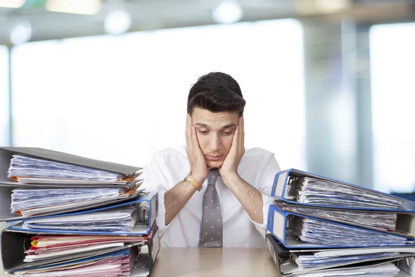 Bored businessman in office with files Stock Image