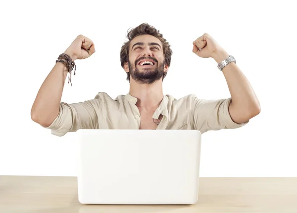 Young man with raised fists using laptop — Stock Photo, Image