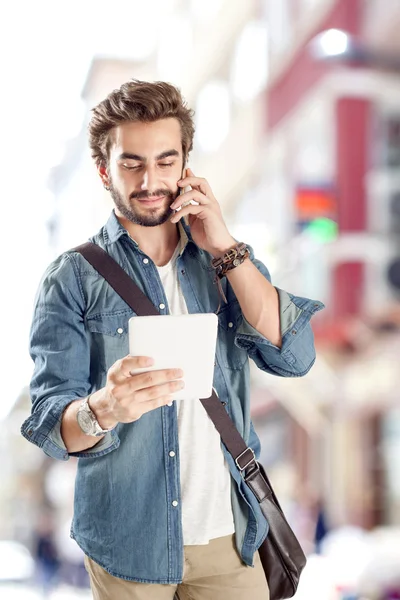 Young man talking mobile phone and holding digital tablet — Stock Photo, Image