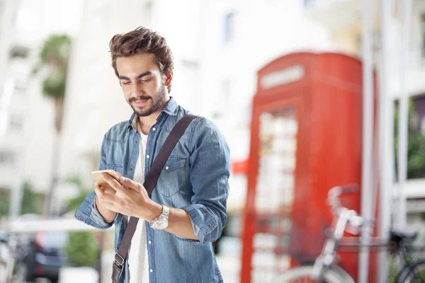 Молодой человек использует мобильный телефон на улице — стоковое фото