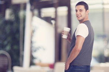 Elinde bir fincan kahve tutan genç adam.