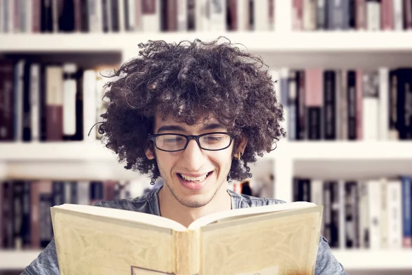 Giovane studente lettura libro in biblioteca — Foto Stock