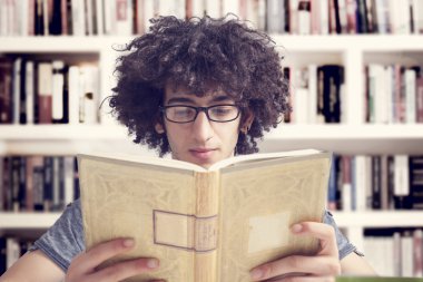 Kütüphanede kitap okuyan genç bir öğrenci