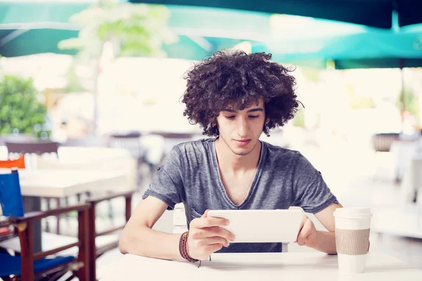 Молодой человек держит цифровой планшет в кафе — стоковое фото