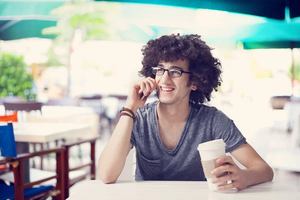 Joven hablando por teléfono y tomando café en la cafetería — Foto de Stock