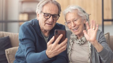 Video görüşmesi için akıllı telefon kullanan yaşlı çift