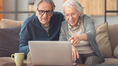 Evde bilgisayar kullanan yaşlı bir çift.