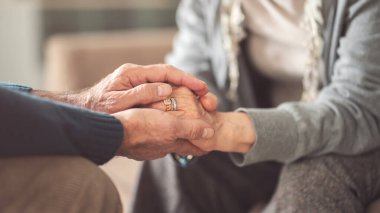 Yaşlı çift el ele tutuşup birbirlerine destek oluyor.