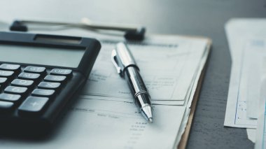 Hesap makinesi ve belgeler masada.