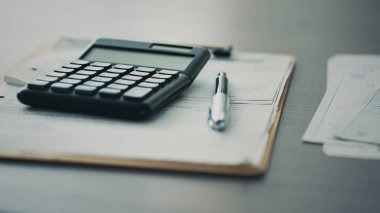 Hesap makinesi ve belgeler masada.
