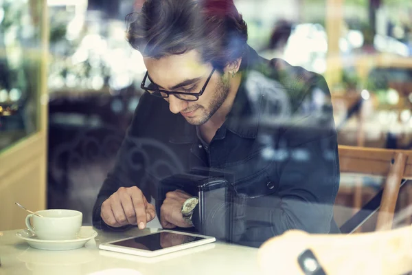 Mladý muž pomocí digitálních tabletu v kavárně — Stock fotografie