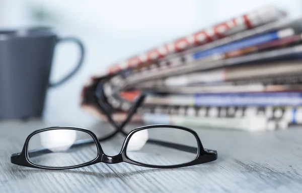 Stack of newspapers, eyeglasses on table — Stock Photo, Image