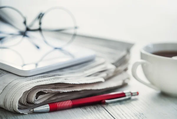 Stack of newspapers, eyeglasses and digital tablet — Stock Photo, Image