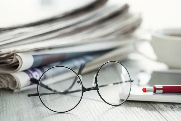 Stack of newspapers, eyeglasses and digital tablet — Stock Photo, Image