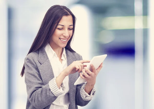 Sorrindo mulher de negócios segurando um computador tablet no escritório — Fotografia de Stock
