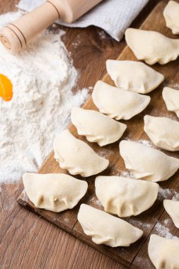 Tahta tahtada, un ve kırık yumurta serpiştirilmiş hamur tatlısı, vareniki ve pierogi yapma süreci. Geleneksel Ukrayna yemeklerine yakından bak. Seçici odak.