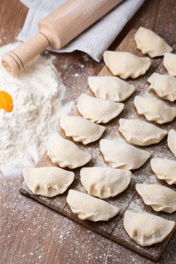 Tahta tahtada, un ve kırık yumurta serpiştirilmiş hamur tatlısı, vareniki ve pierogi yapma süreci. Geleneksel Ukrayna yemeklerine yakından bak. Seçici odak.