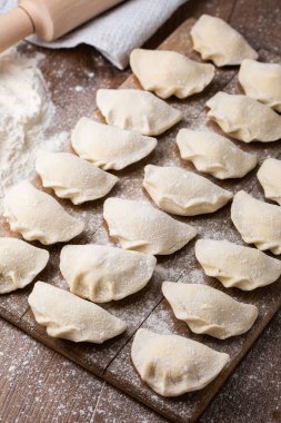 Tahta tahtada, un ve kırık yumurta serpiştirilmiş hamur tatlısı, vareniki ve pierogi yapma süreci. Geleneksel Ukrayna yemeklerine yakından bak. Seçici odak.