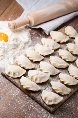 Tahta tahtada, un ve kırık yumurta serpiştirilmiş hamur tatlısı, vareniki ve pierogi yapma süreci. Geleneksel Ukrayna yemeklerine yakından bak. Seçici odak.