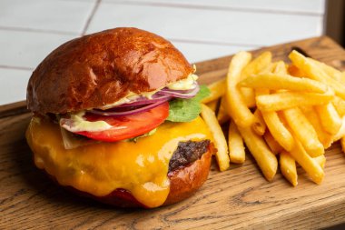 Beyaz arka planda izole edilmiş patates kızartmalı büyük bir çizburger. Hamburger, köfteli soğan, domates, marul turşusu, erimiş çedar, hardal, domates reçeli, mayonez. Yatay