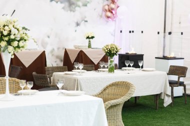 Düğün ziyafeti dekorasyonu geçmişi. Bir parti, düğün resepsiyonu ya da diğer şenlikli etkinlikler için çanak çömlek ve çiçeklerle dolu romantik bir masa. Akşam yemeği için cam eşyalar ve çatal bıçaklar..