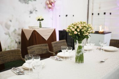 Düğün ziyafeti dekorasyonu geçmişi. Bir parti, düğün resepsiyonu ya da diğer şenlikli etkinlikler için çanak çömlek ve çiçeklerle dolu romantik bir masa. Akşam yemeği için cam eşyalar ve çatal bıçaklar..