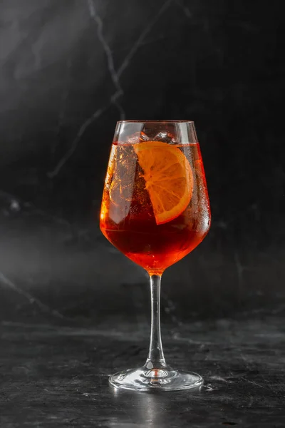 冷たい氷のガラスワイングラスで提供されるアペロールスプリッツカクテル オレンジとバジルの葉のスライスで飾られました — ストック写真